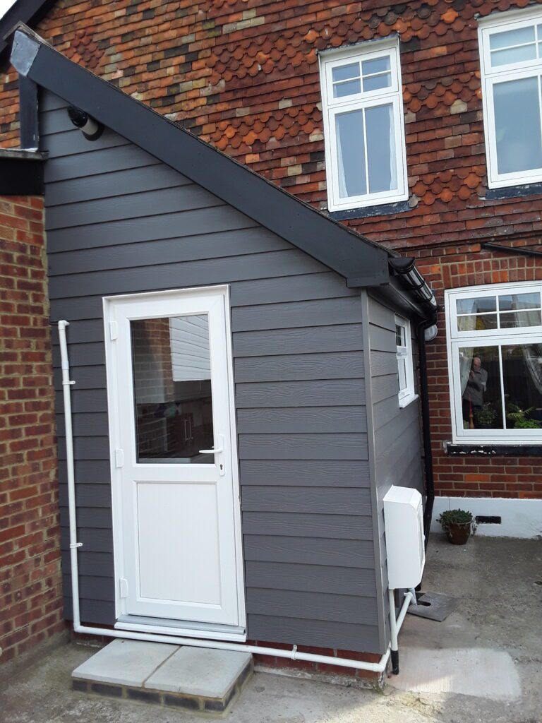Grey weatherboard cladding installed on the side of a house by J Burgoyne Limited